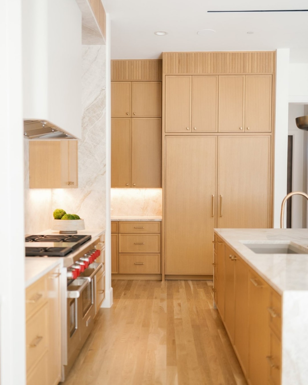 Kitchen with white-oak cabinets, a wood island with marble top and a professional range.